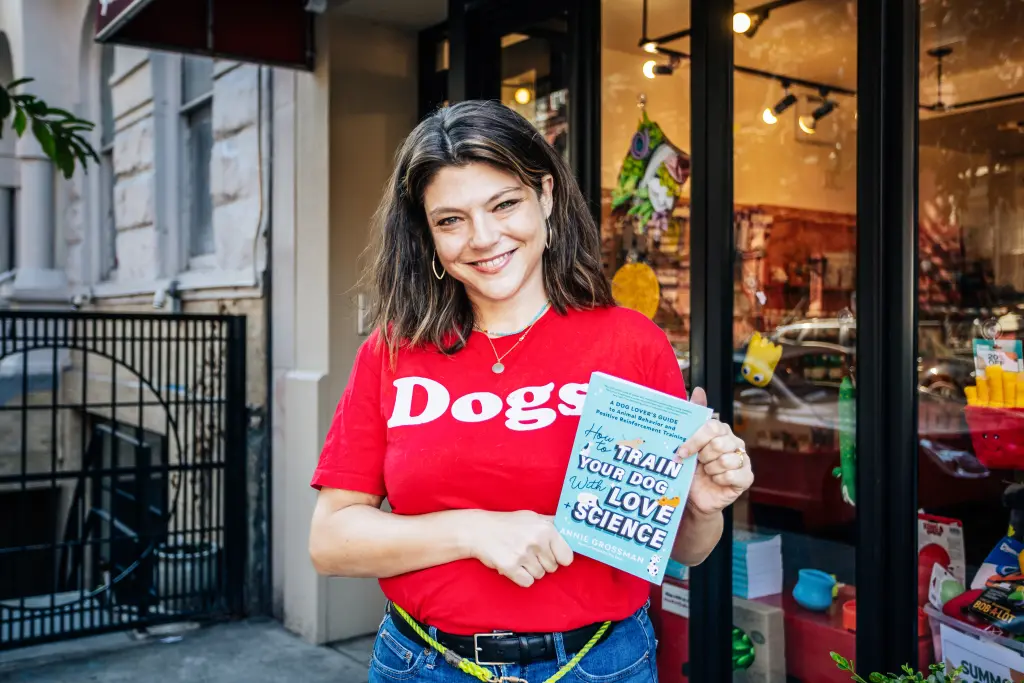 Annie Grossman holding her book How to Train Your Dog with Love + Science