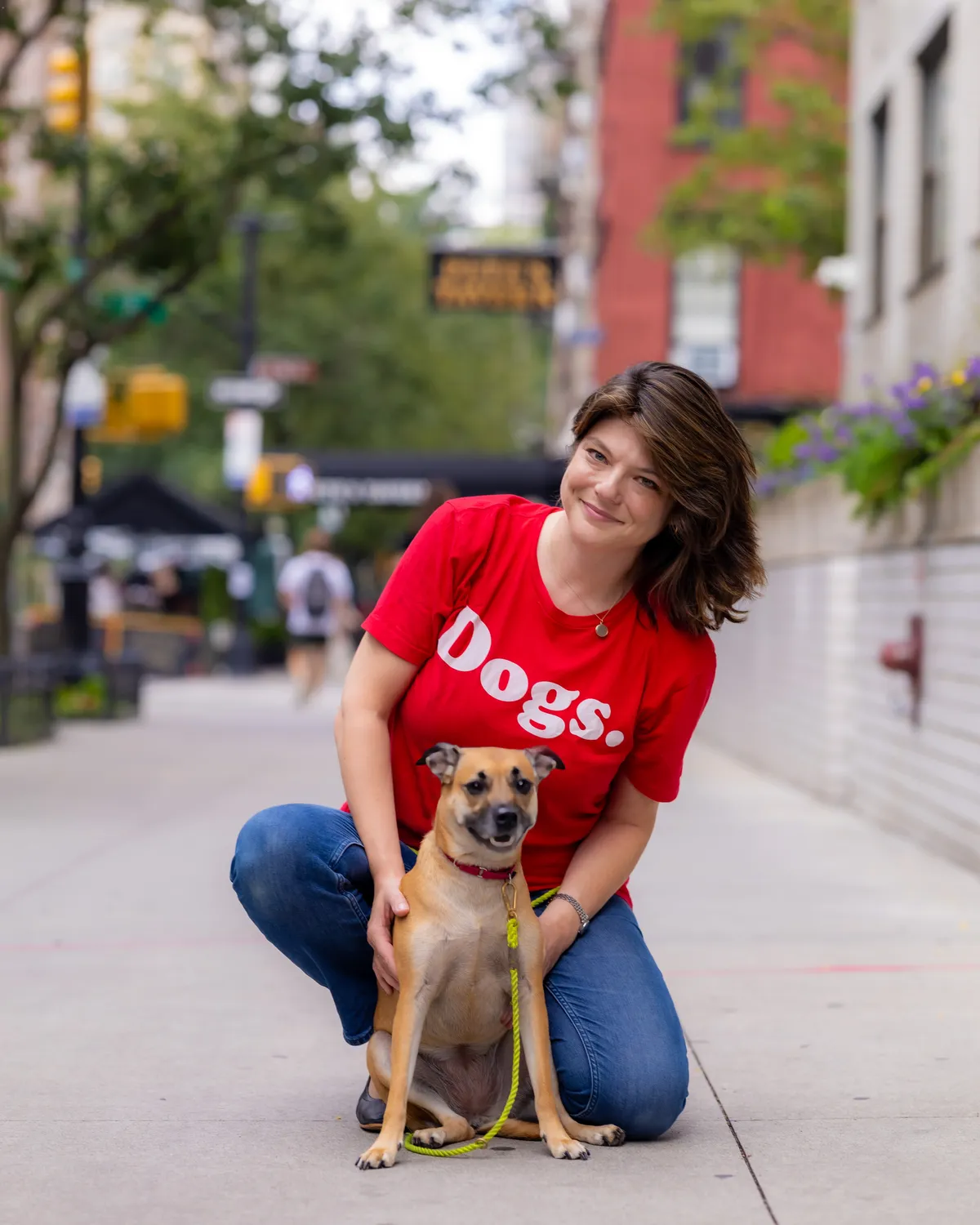 Annie Grossman crouching with a dog on an NYC sidewalk