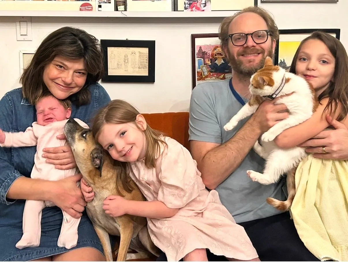 A family with three young children and two dogs on a couch