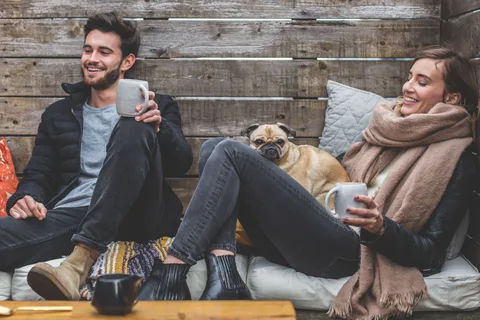 Two friends relaxing with a pug between them